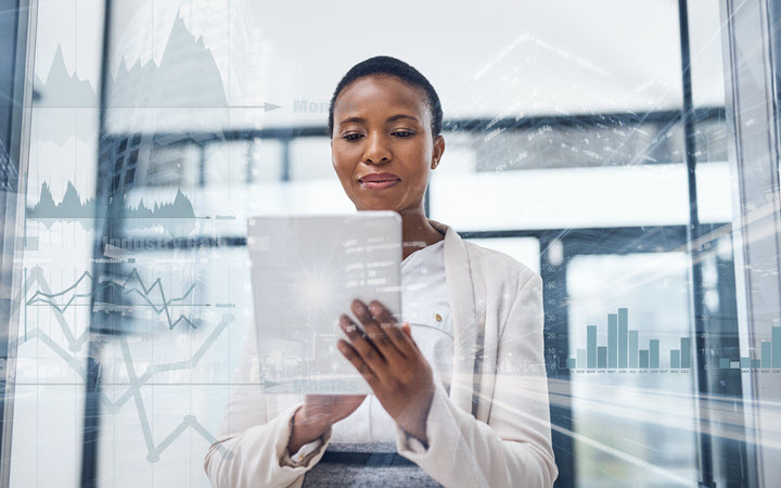 A woman in business attire looks at a tablet screen.